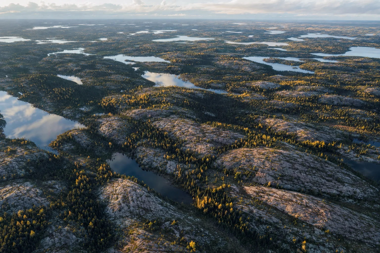 Aerial view of Canadian boreal forest, granite bedrock and scattered lakes in autumn